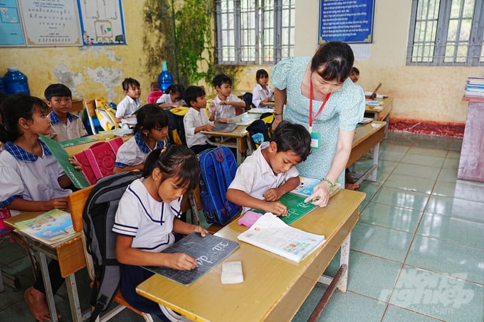 Cô giáo Lê Thị Mai đang 'cầm tay chỉ cách viết' cho học sinh. Ảnh: Phúc Lập.